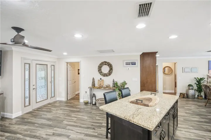 Kitchen featuring wood finished floors, a breakfast bar, crown molding, a center island, and recessed lighting