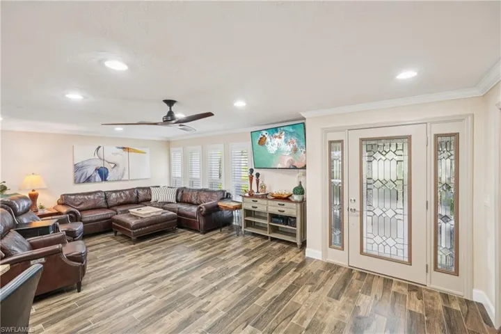 Living room with crown molding, wood finished floors, a ceiling fan, and recessed lighting