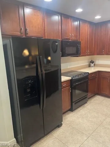 Kitchen featuring black appliances, light countertops, light tile patterned floors, and recessed lighting