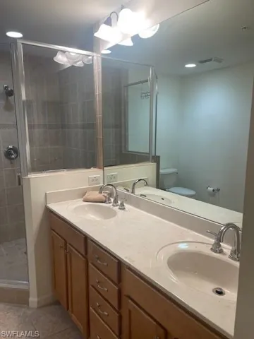 Bathroom with a stall shower, double vanity, light tile patterned floors, and recessed lighting