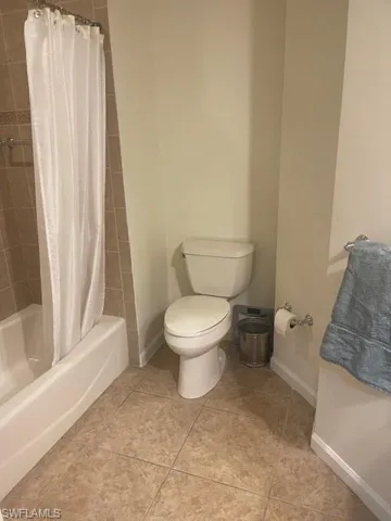 Bathroom featuring shower / tub combo with curtain and light tile patterned flooring