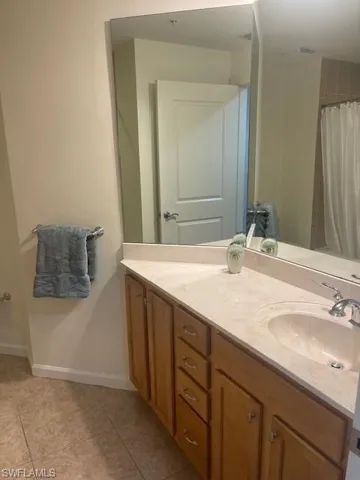 Bathroom featuring vanity, light tile patterned flooring, and curtained shower