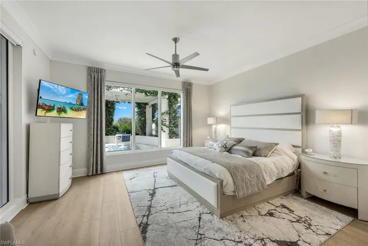 Spacious primary suite with floor to ceiling windows, wood flooring and tranquil views.