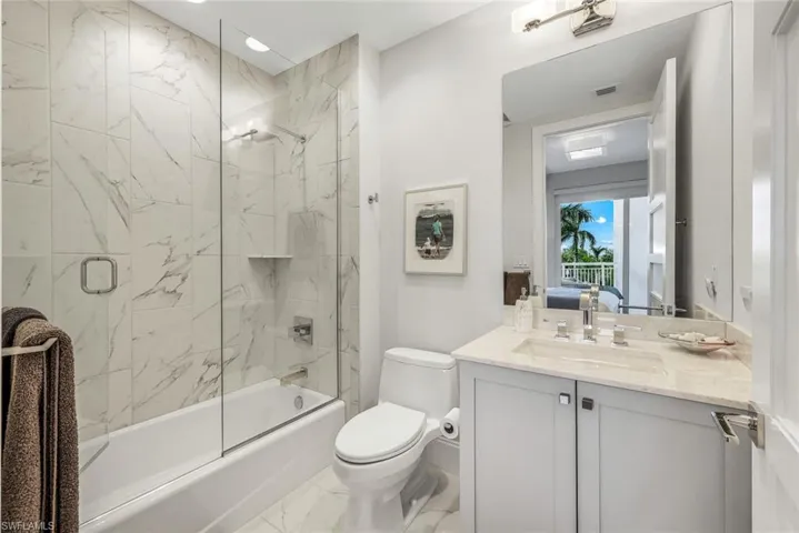 En suite guest bath with frameless glass shower and modern tilework.