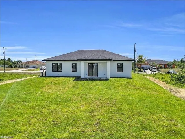 Contemporary ranch-style residence featuring a white stucco exterior, dark shingle roof, and black-framed windows