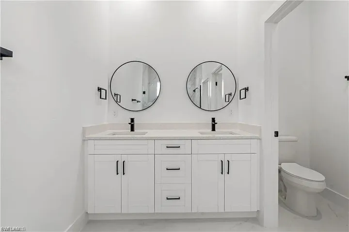 Dual vanity with white cabinetry, light-toned countertop, and matte black fixtures