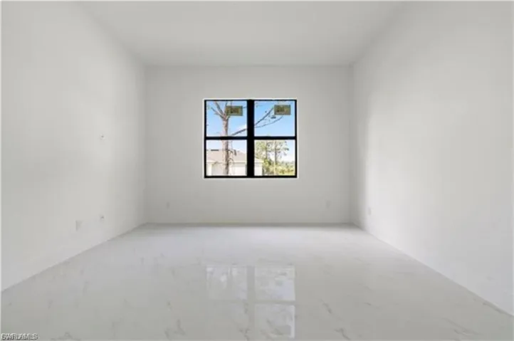 Spacious room featuring a large black-framed window, white walls, white baseboards, and polished tile flooring