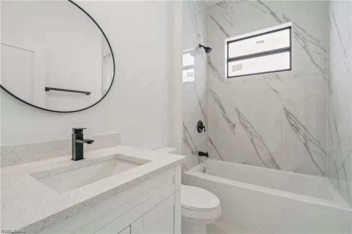 Contemporary bathroom featuring a white vanity with an integrated sink, speckled stone countertop, and matte black faucet