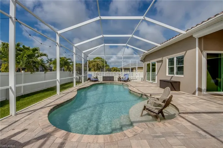 View of pool with a sunroom, patio surround, a fenced backyard, and glass enclosure