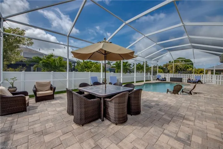 View of pool with outdoor dining area, a sunroom, a lanai, patio surround, and a fenced backyard