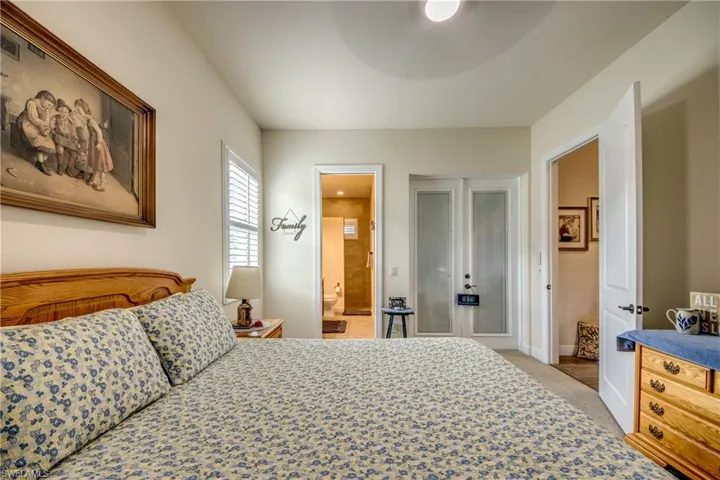 Bedroom featuring ensuite bath, a ceiling fan, and light colored carpet