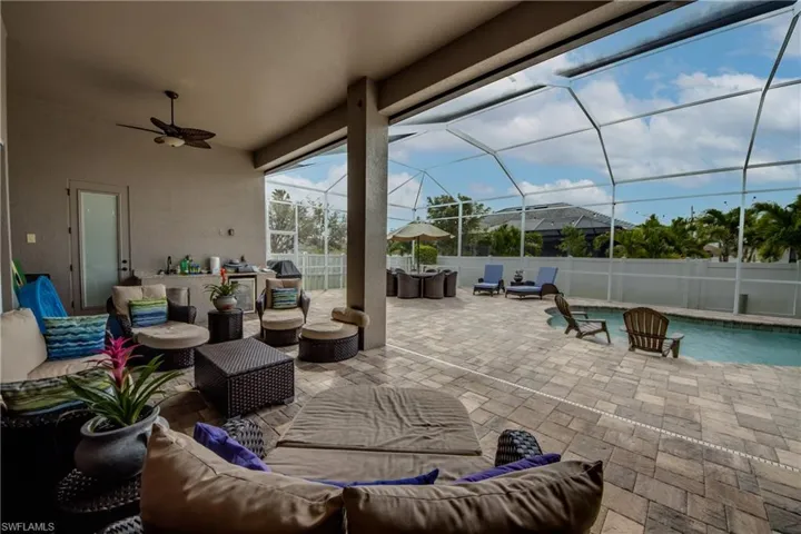 Fenced backyard featuring outdoor furniture, a patio area, ceiling fan, a sunroom, and glass enclosure