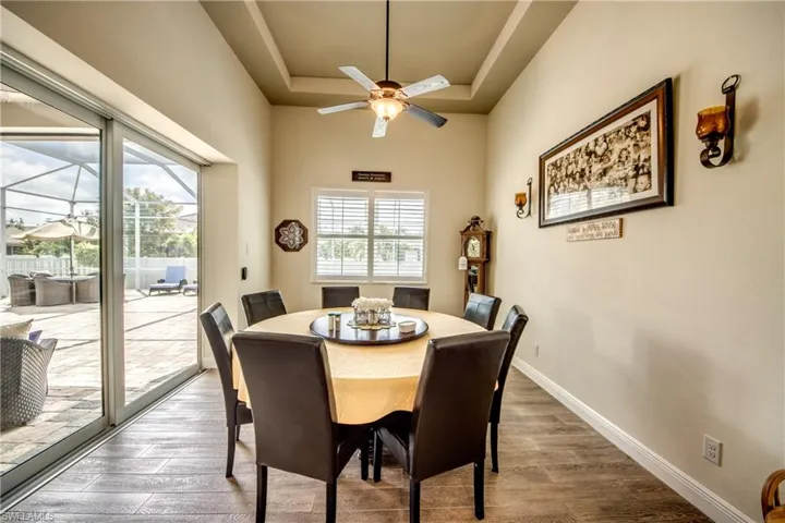 Dining space with a tray ceiling, wood finished floors, ceiling fan, and a sunroom