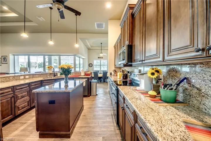 Kitchen with a ceiling fan, decorative light fixtures, a raised ceiling, a kitchen island, and stainless steel appliances