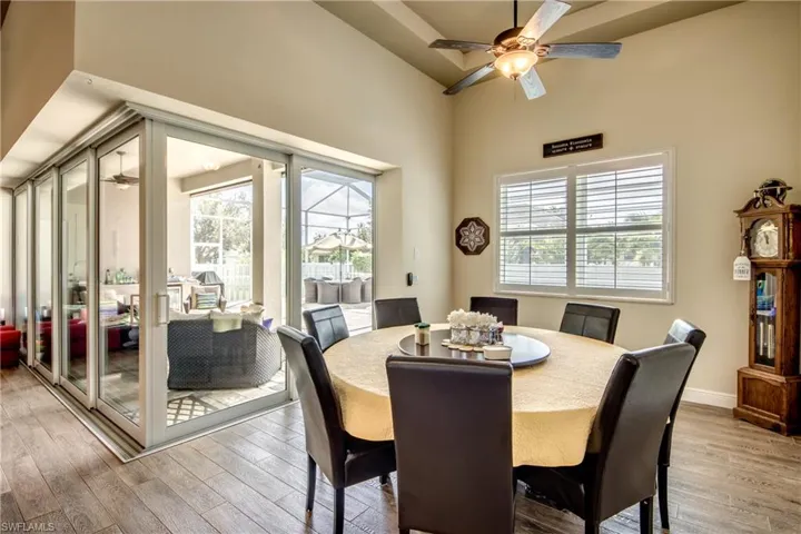 Dining space with ceiling fan, light wood-style floors, and a high ceiling