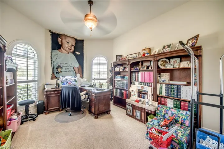 Office space featuring light carpet and a ceiling fan
