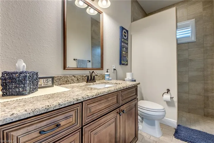 Full bath with vanity, a textured wall, and a walk in shower