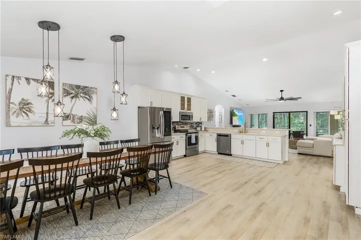 Kitchen with stainless steel appliances, kitchen peninsula, light wood-type flooring, and decorative light fixtures