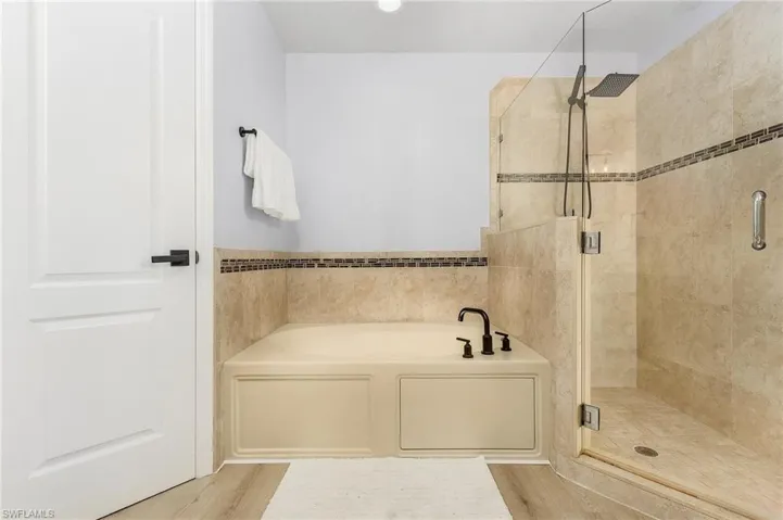 Bathroom featuring shower with separate bathtub and wood-type flooring