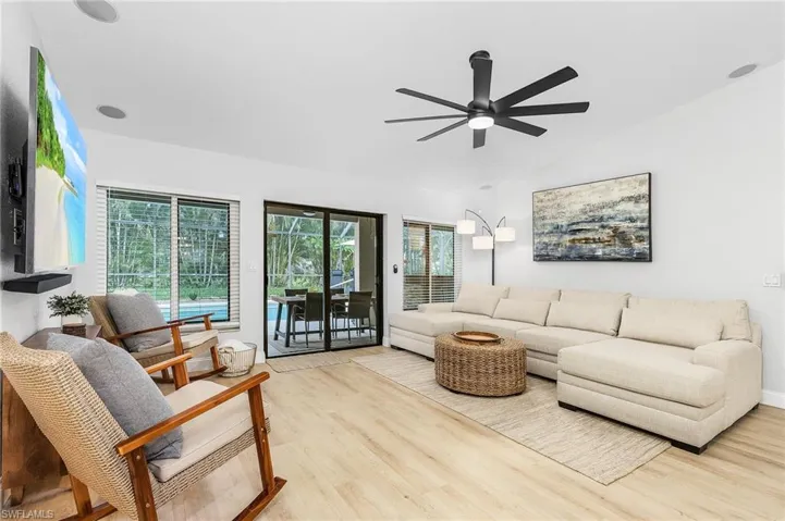 Living room with vaulted ceiling, ceiling fan, and light hardwood / wood-style flooring