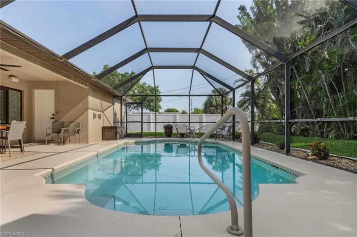 View of pool with glass enclosure, ceiling fan, and a patio area
