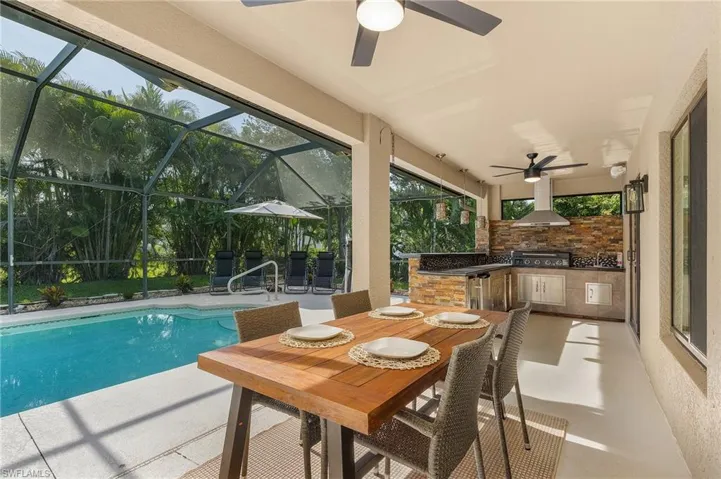 View of pool with a grill, a lanai, a patio area, ceiling fan, and exterior kitchen