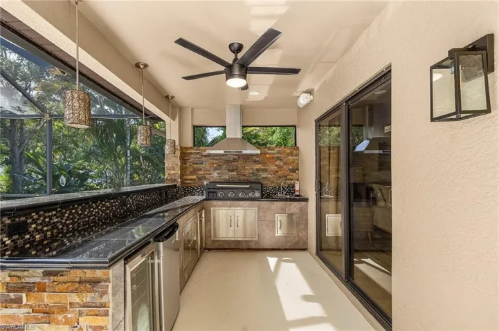 View of patio / terrace featuring ceiling fan, grilling area, an outdoor kitchen, and glass enclosure