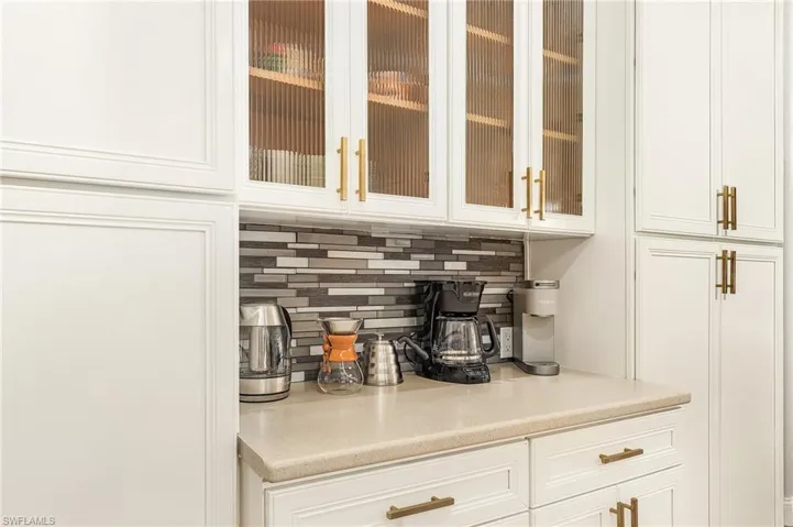 Bar with white cabinetry and tasteful backsplash