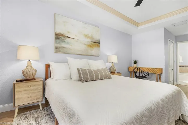 Bedroom with ornamental molding, wood-type flooring, ensuite bath, and ceiling fan