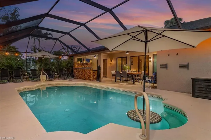 Pool at dusk with a lanai and a patio