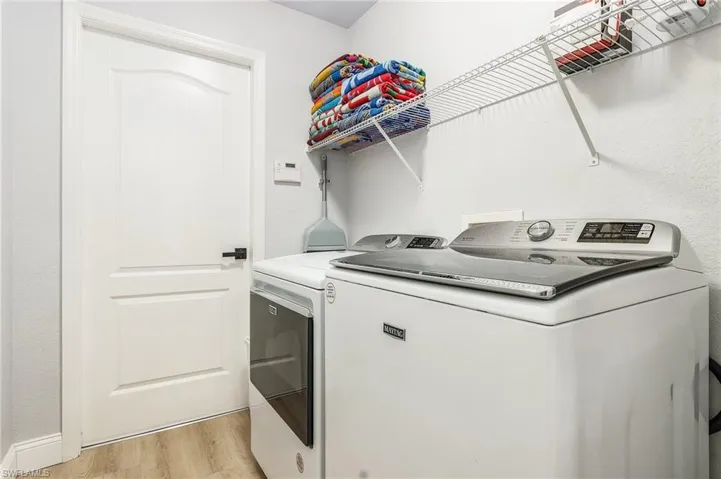 Clothes washing area featuring light wood-type flooring and washing machine and dryer