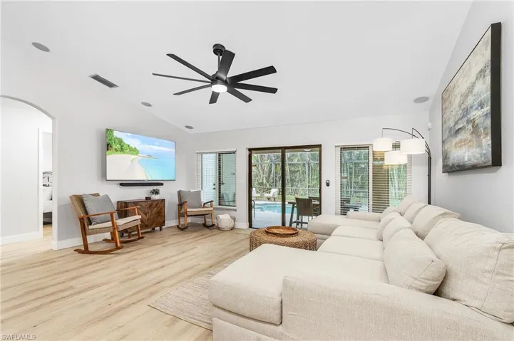 Living room featuring light hardwood / wood-style floors, lofted ceiling, and ceiling fan