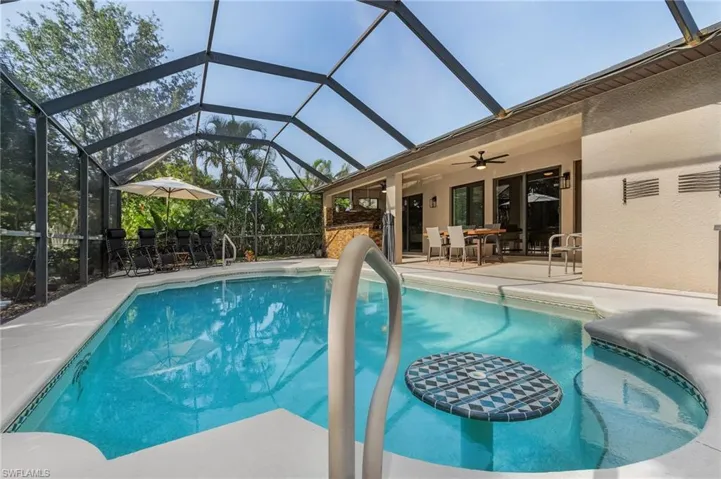 View of pool with ceiling fan, glass enclosure, and a patio