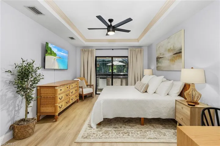 Bedroom featuring light hardwood / wood-style floors, a tray ceiling, ceiling fan, and access to exterior
