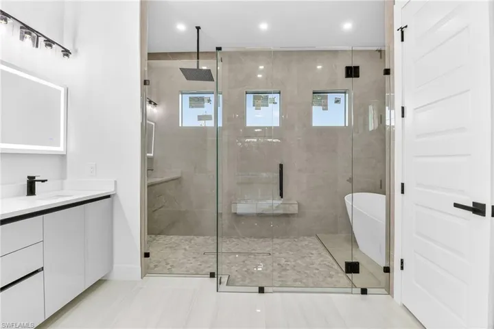Full bathroom featuring a shower stall, vanity, a soaking tub, plenty of natural light, and recessed lighting