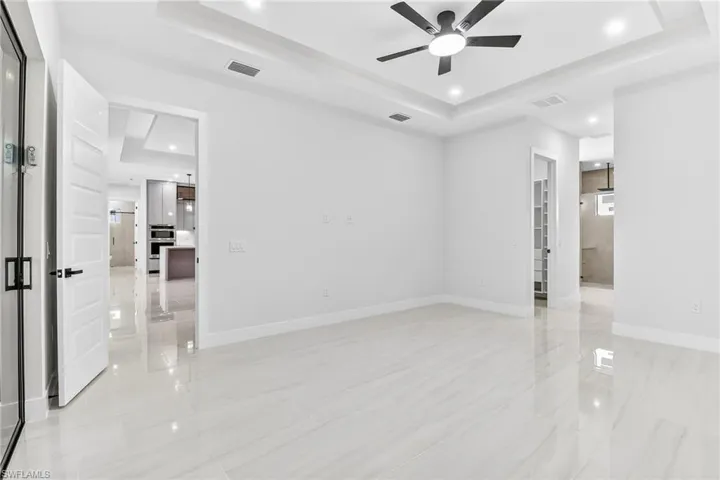 Primary bedroom featuring a tray ceiling, recessed lighting, and a ceiling fan