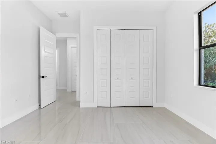 Unfurnished bedroom featuring multiple windows and a closet