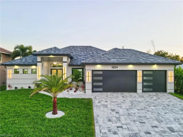 View of front of property featuring a lawn, decorative driveway, stucco Block Structure, and an attached garage