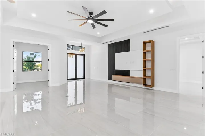 Unfurnished living room with a tray ceiling, ceiling fan, and recessed lighting