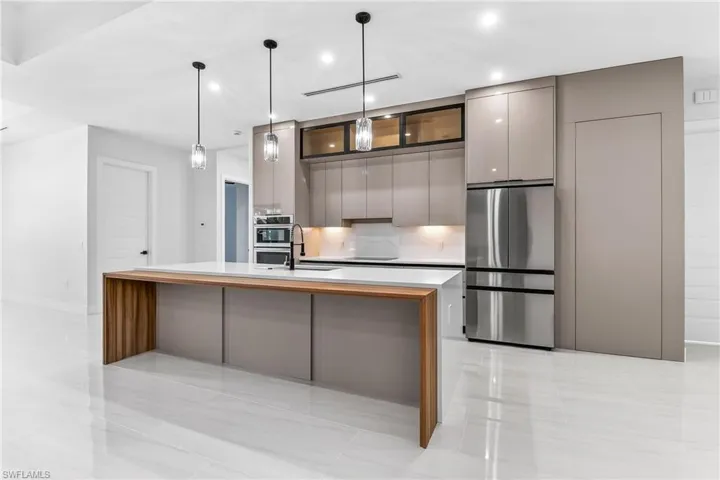 Kitchen featuring gray cabinets, modern cabinets, stainless steel appliances, and a kitchen island with sink