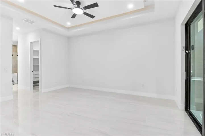 Primary bedroom with a tray ceiling, a ceiling fan, and recessed lighting