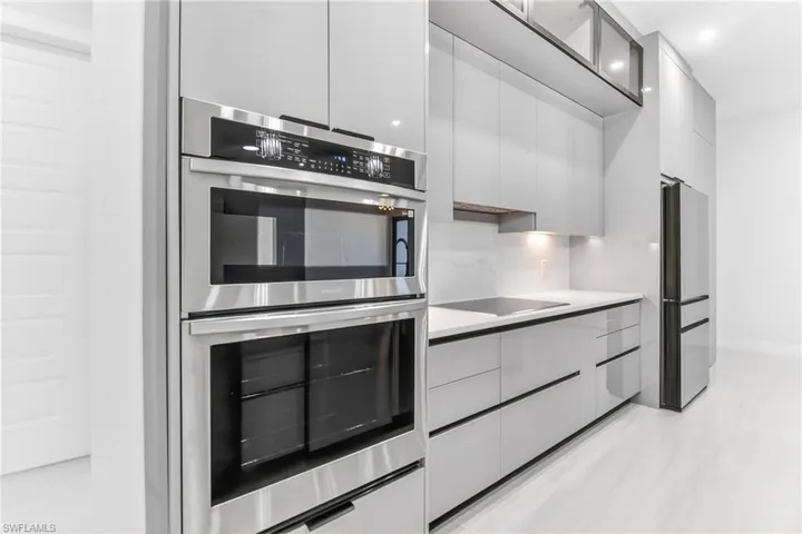 Kitchen featuring stainless steel appliances, modern cabinets, light countertops, and recessed lighting