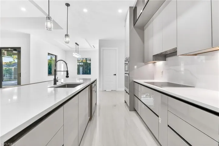 Kitchen with decorative light fixtures, modern cabinets, light stone counters, white cabinetry, and black electric cooktop