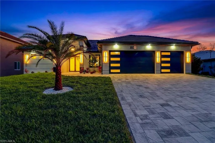 View of front of property with a front lawn, driveway, an attached garage, and stucco Block Structure.