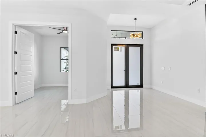 Foyer entrance  and office /den with french doors, ceiling fan, and suspended lighting