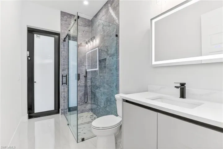Full bath featuring vanity and a stall shower leads to pool area