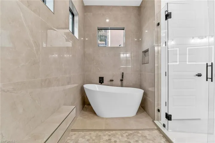 Bathroom with tile walls, a freestanding bath, and tile patterned floors