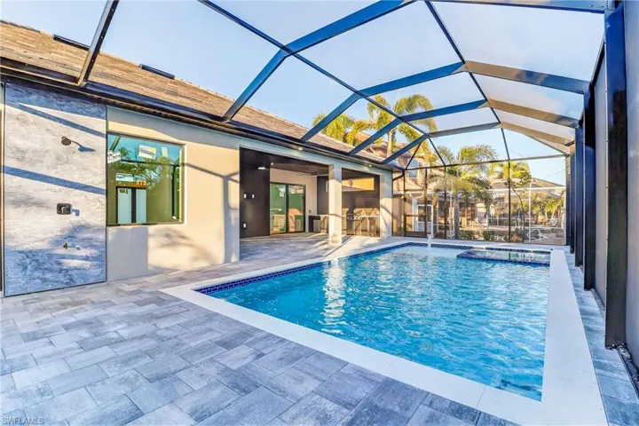 Relaxing pool / spa featuring a full screened in patio area and exterior kitchen