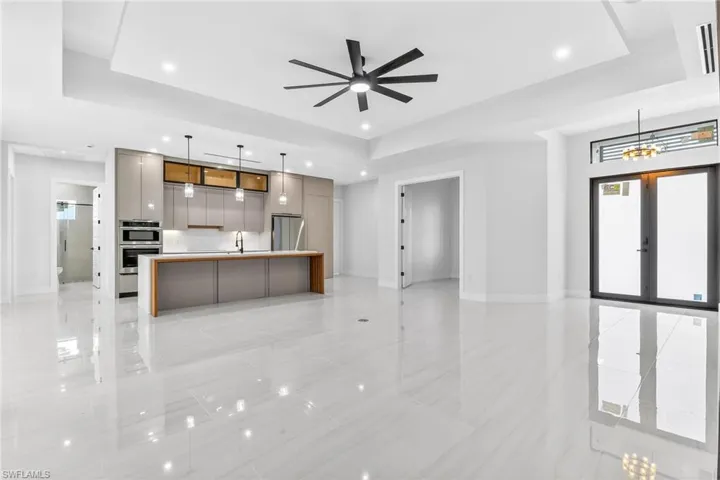 Kitchen with modern cabinets, open floor plan, a spacious island, a tray ceiling, and decorative light fixtures