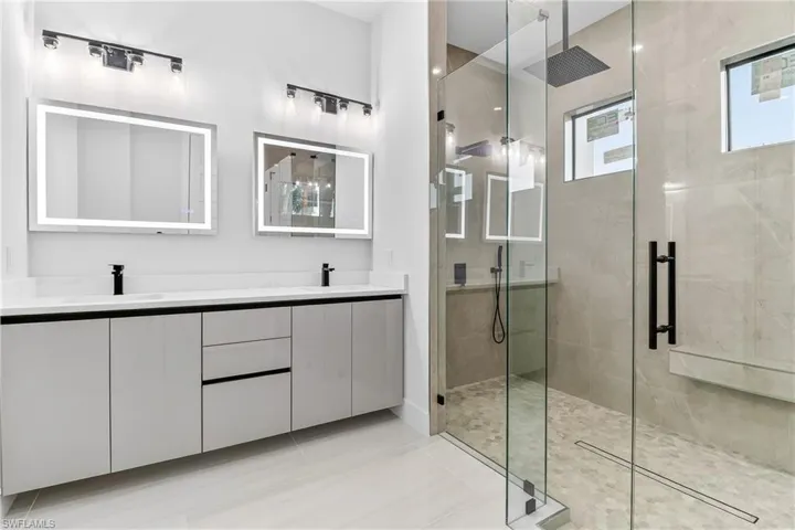 Bathroom featuring a stall shower, double vanity, and light tile luxurious flooring